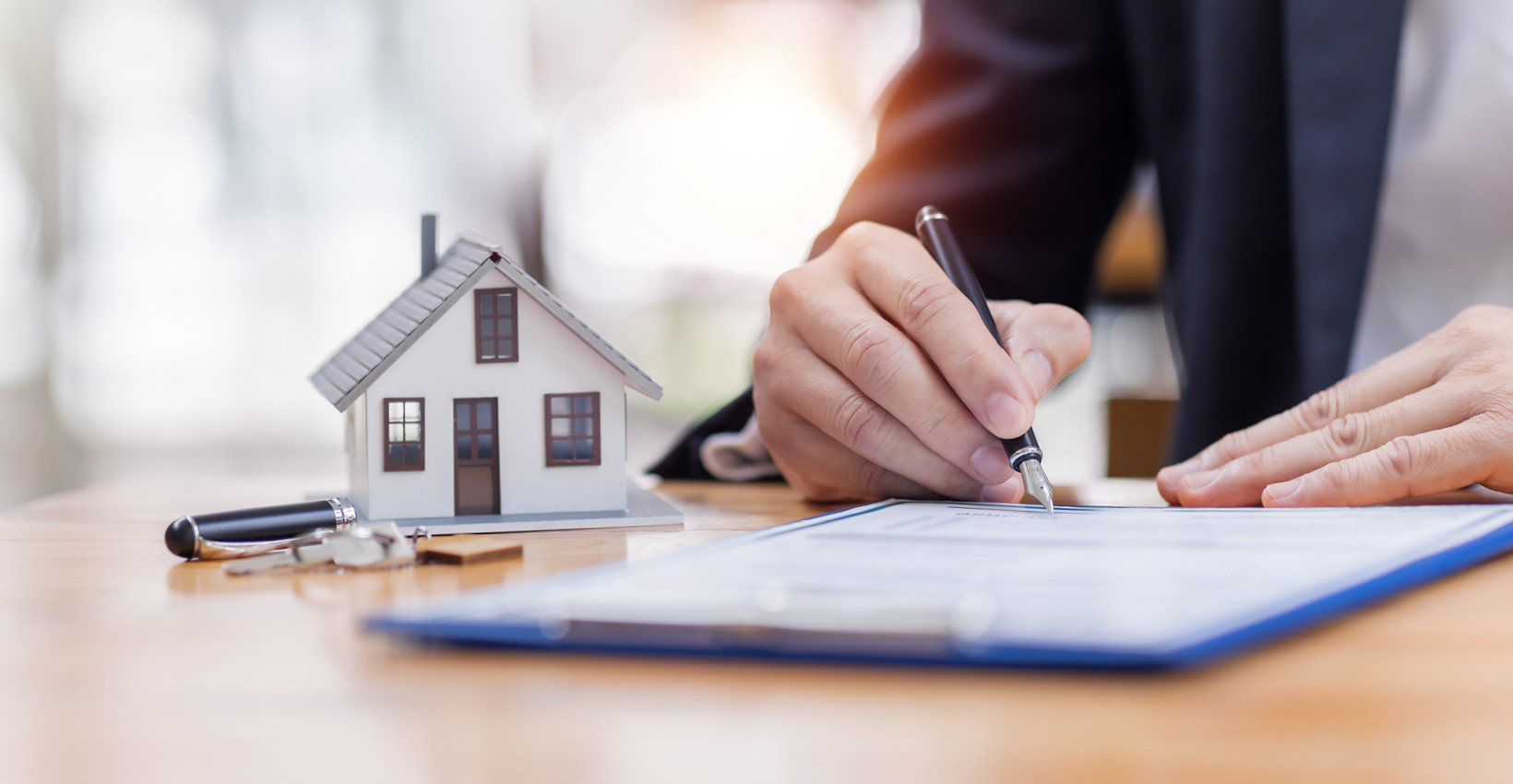 a person writes on a piece of paper next to a tiny house