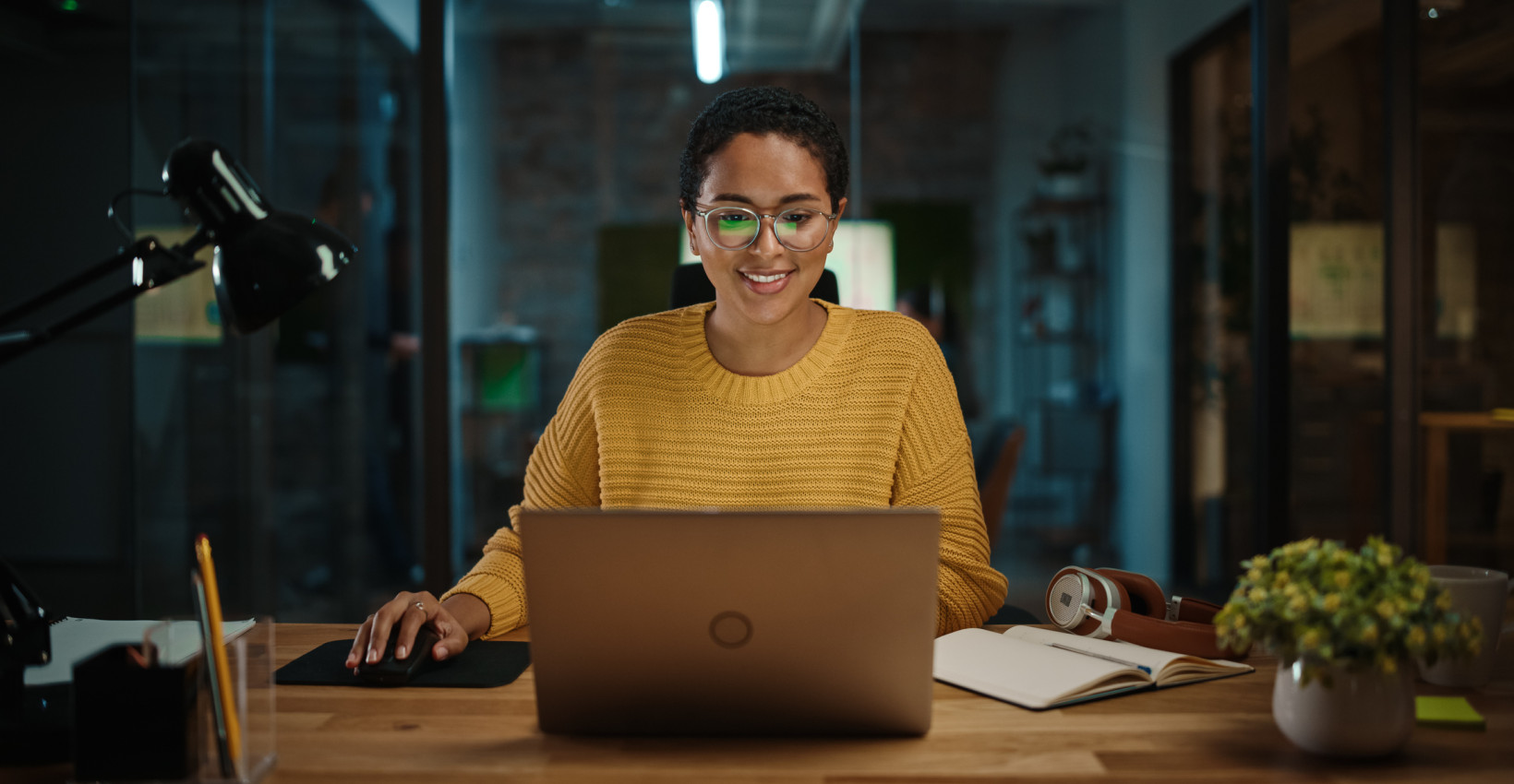 a woman sits at a table with her laptop