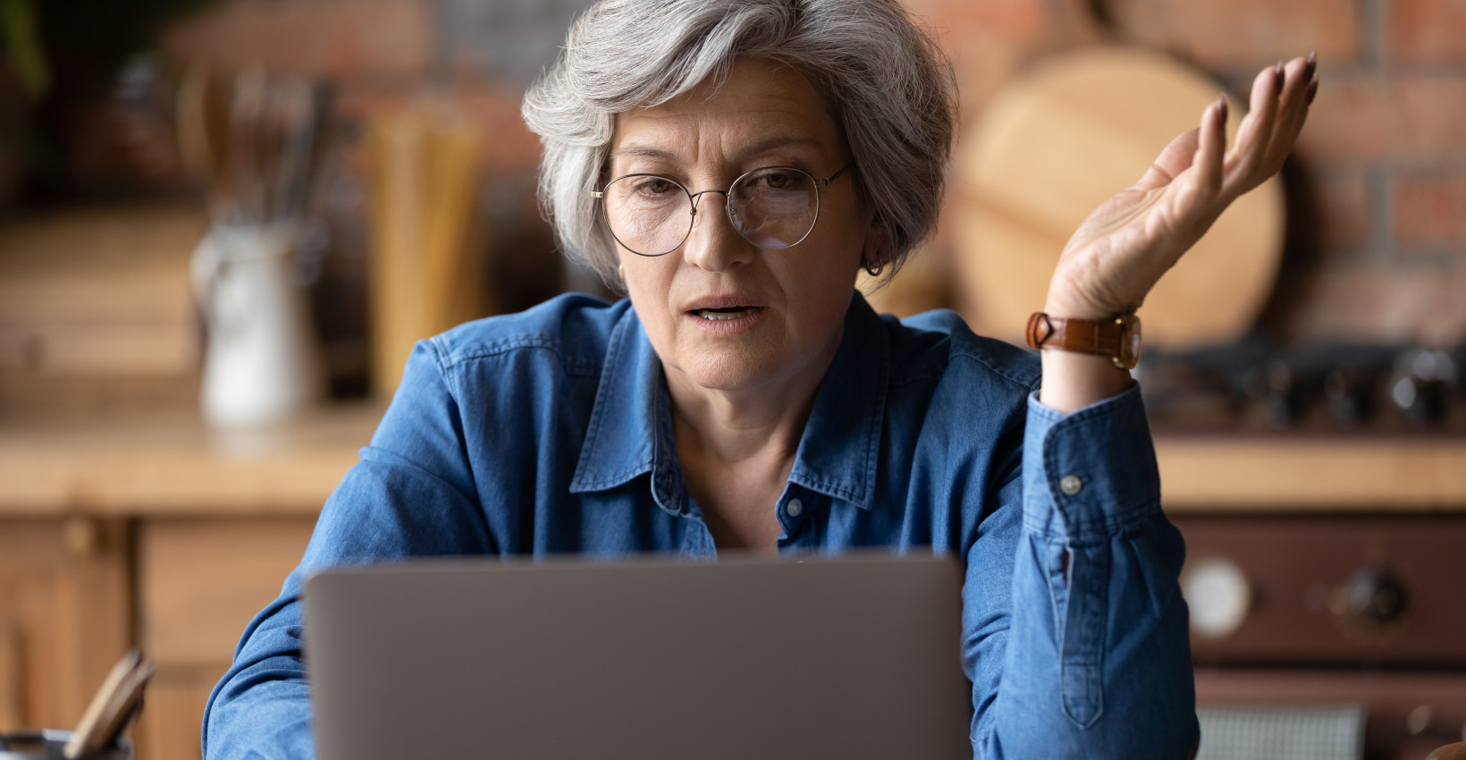 an older woman sits at her computer with a frustrated expression