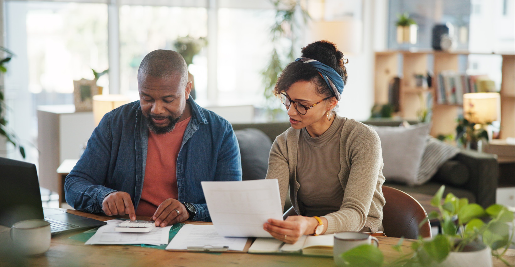 a black man and woman sit together at a table looking at paperwork in front of them