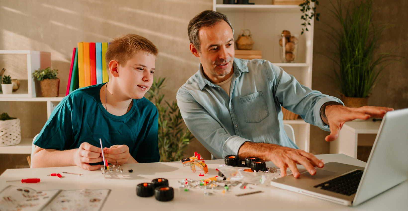 a father and son sit together at a laptop