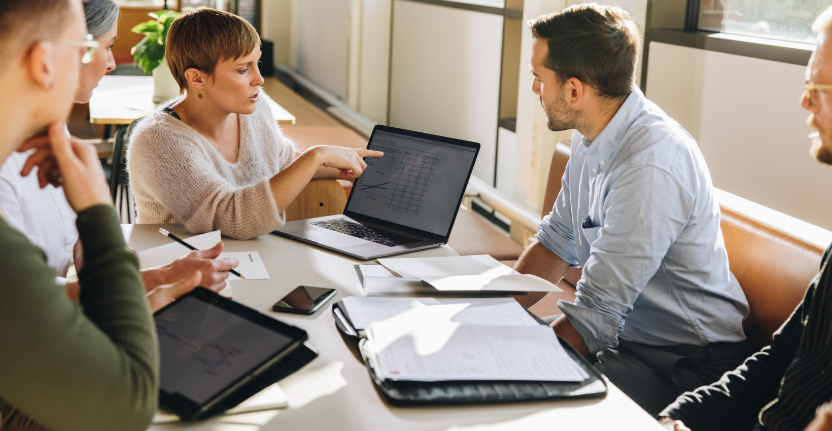 Colleagues sit around a desk looking at a laptop screen
