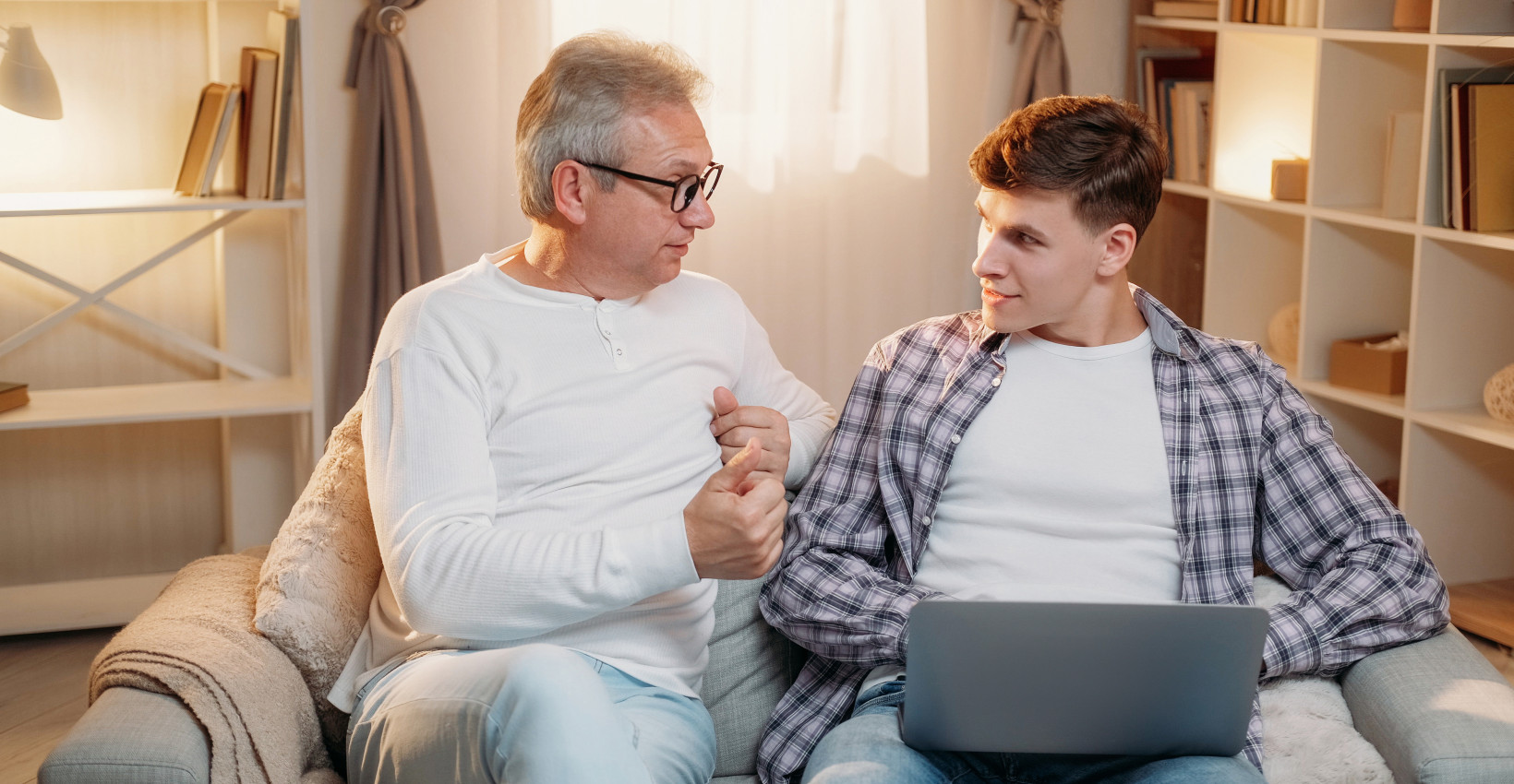 a father and son sit together looking at a laptop