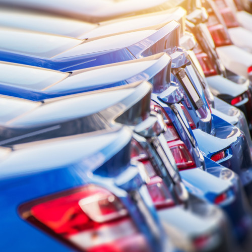A line of blue cars at a dealership