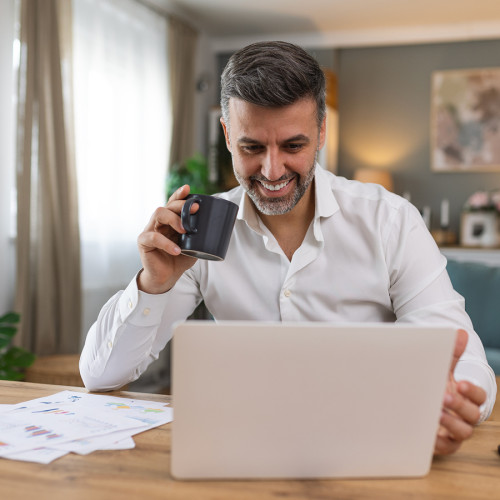 A man smiles as he looks at his laptop