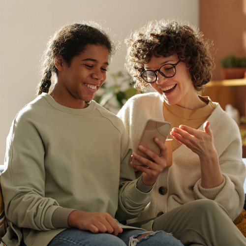 A mom and daughter smile as they look at a phone