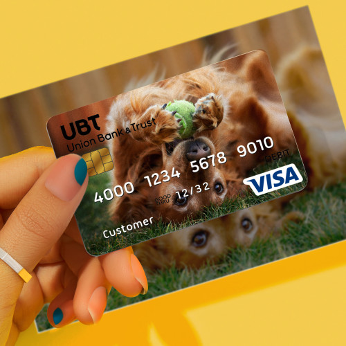 Someone holding a UBT debit card over the top of the same photo on the table