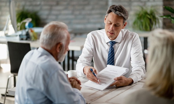 an older couple sit with a younger man at a desk mid conversation
