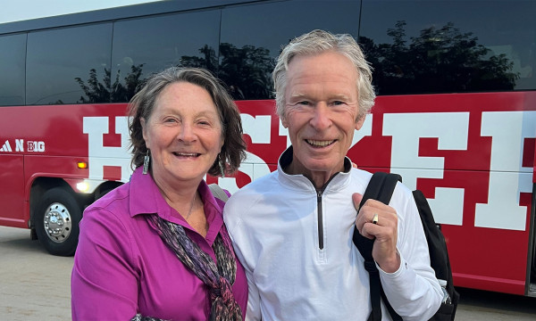 two people stand in front of a bus smiling