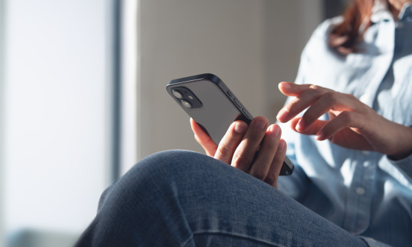 A woman holding her phone and tapping it