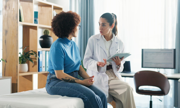 a female doctor sits with a female patient in an exam room
