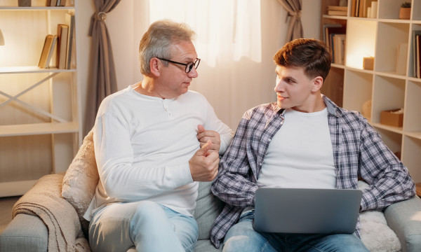 a father and son sit together looking at a laptop